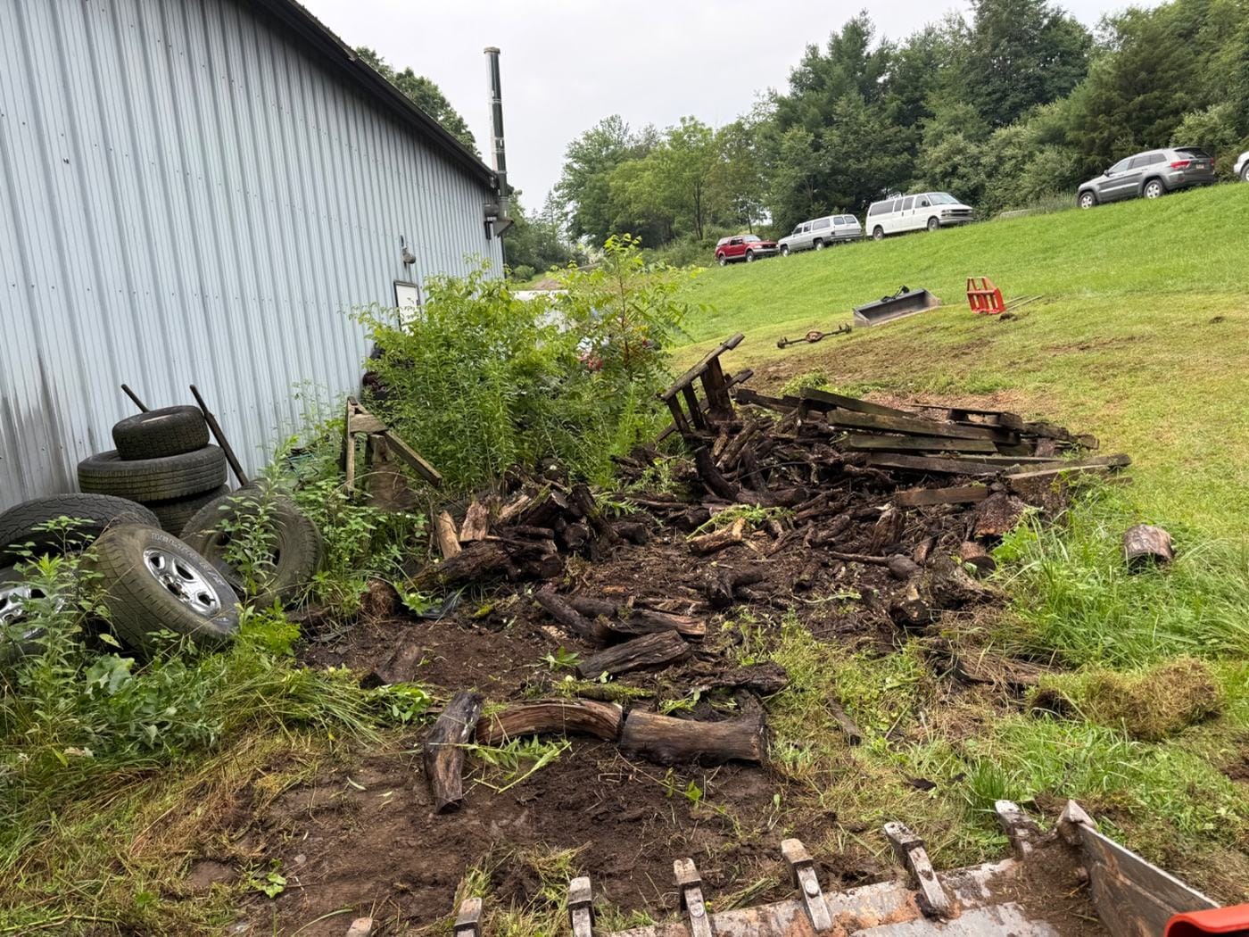 Rotted wood and old boards pulled out along a metal building.