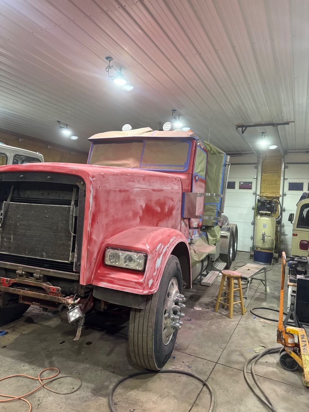 A red semi tractor in the shop bay.
