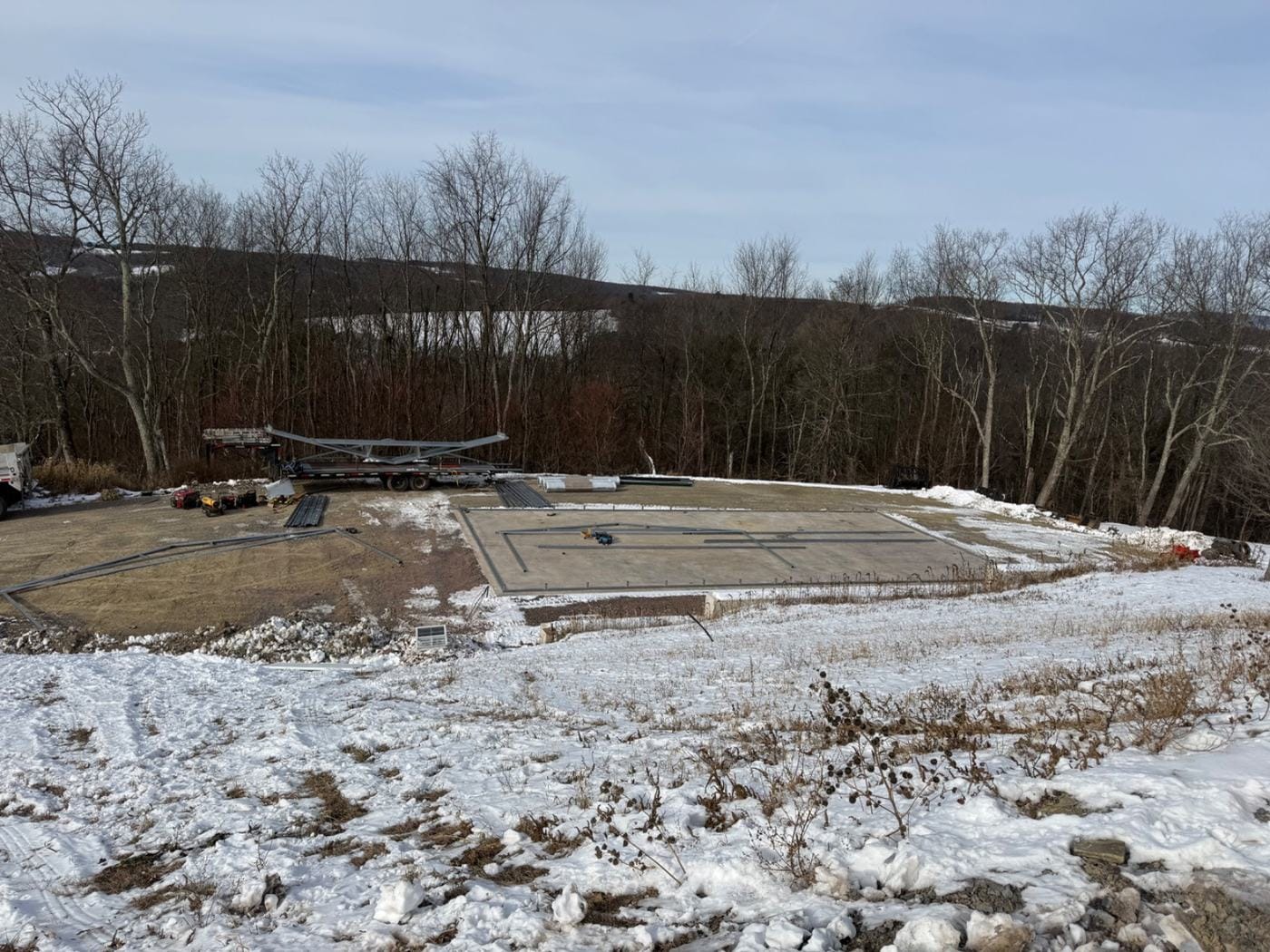 A level building pad with the slab laid out, in the snow.