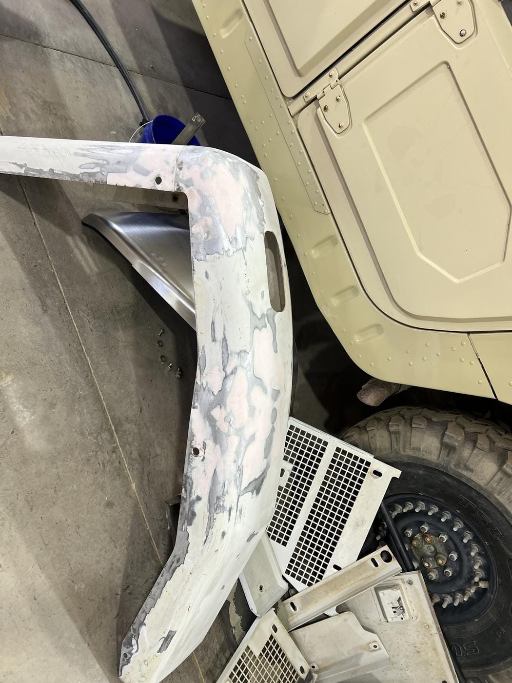 A fender in primer on the shop floor, next to a tan truck.