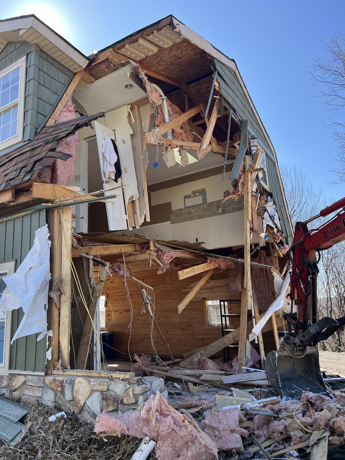 An excavator tearing down a two-story building.